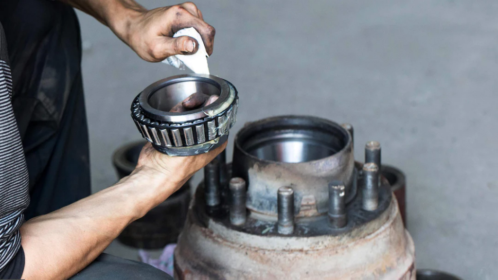 A technician is lubricating the bearing, as insufficient lubrication is a common cause of bearing noise issues